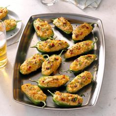 several stuffed peppers on a metal tray with beer in the backgroung area