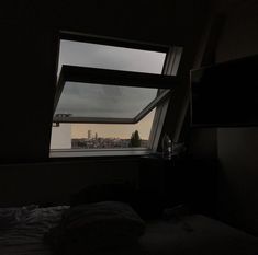 a bedroom with a window that looks out onto the city