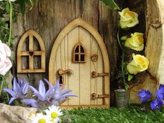 a wooden fairy house with flowers surrounding it