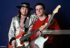 two men are posing with guitars in their hands