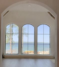 an empty room with three large windows overlooking the ocean