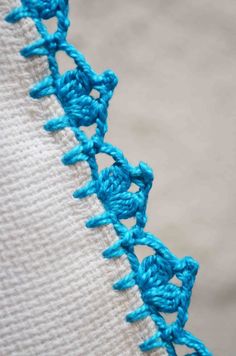 a close up view of the crochet stitching on a white cloth with water in the background