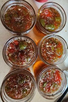 six jars filled with food sitting on top of a table