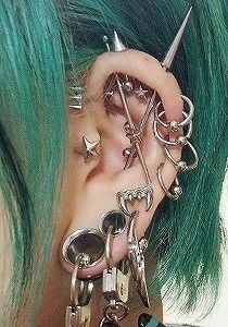 a woman with green hair has some piercings on her ear