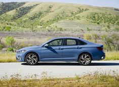 the blue car is parked on the side of the road in front of some hills