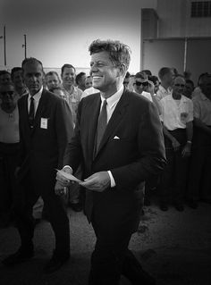 a black and white photo of a man walking in front of a group of people