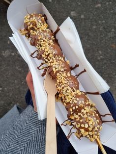 a person holding a paper container filled with chocolate covered donut and sprinkles