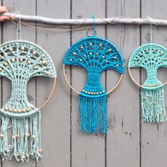 three crocheted dream catchers hanging on a wooden wall, one is blue and the other is green