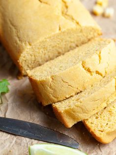 sliced loaf of cornbread next to a knife and some limes on a piece of paper