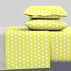 three pillows are stacked on top of each other in front of a yellow and white polka dot pattern