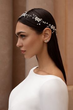 a woman with long hair wearing a white dress and a headband that has flowers on it