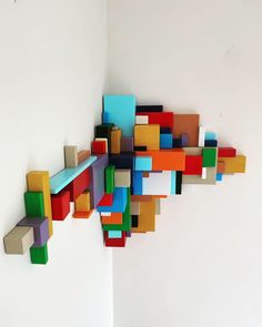 colorful blocks are arranged in the shape of an abstract structure on a white wall,