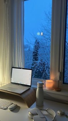 a laptop computer sitting on top of a desk next to a window