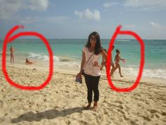 a woman standing on top of a sandy beach next to the ocean with red circles in front of her