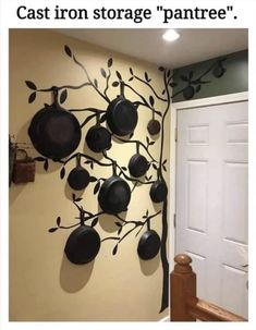 a tree with pots and pans hanging on it's branches in front of a door