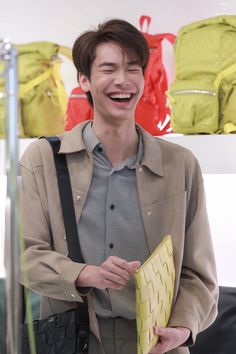 a young man smiles while holding a folder