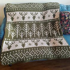 a crocheted blanket sitting on top of a blue couch next to a pillow