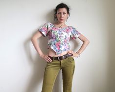 Super-cute 80's cropped blouse with short sleeves. Made in USA by S. L. Petites. Blooming roses painting print in soft pink and blue on white. Buttons down the front. Fabric: 100% cotton. Short raglan sleeves. Cropped length and pointed waist. Tagged size US10. Estimated size XS to S, the model is size XS, please make your judgement from the measurements below: armpit  ~ 90 cm  /  ~ 35 " waist  ~ 78 cm  /  ~ 30 " length  ~ 43 cm  /  ~ 17 " by the back In great vintage condition. 90s Style Short Sleeve Crop Top For Summer, Retro Fitted Short Sleeve Crop Top, Vintage Short Sleeve Crop Top For Spring, Retro Short Sleeve Crop Top For Spring, Vintage Fitted Cropped Blouse, Fitted Cropped Vintage Blouse, Vintage Fitted Cropped Top, Fitted Vintage Cropped Top, Fitted Cropped Vintage Crop Top