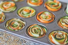 the muffin tins are filled with assorted rolled up cupcakes