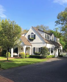 a white house with black shutters and trees