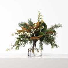 a vase filled with flowers and greenery on top of a table