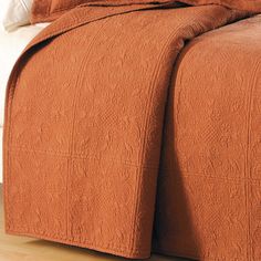 an orange bedspread on a bed with white pillows