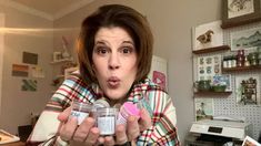 a woman making a funny face while holding two jars in front of her mouth and looking at the camera