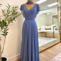 a blue dress is on display in front of a mirror and a potted plant