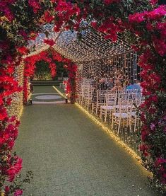 an outdoor wedding venue with red flowers on the aisle and white chairs in the middle