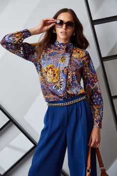 Embrace the playful elegance of our Jaden Print in a palette of sophisticated hues. Modern with its draped neckline, this romantic long sleeve shirt is perfect for day to night. Pair it with Vegan Leather or our pleated crepe pants in twilight. Printed Long Sleeve Draped Neck Top 91% Silk, 9% Spandex Runs true to size. Model is 5'9" and wearing size S Dry Clean Only Imported Style #: ETR44207 Chic Multicolor Long Sleeve Blouse, Elegant Printed Blue Blouse, Elegant Blue Printed Blouse, Elegant Multicolor Tops For Workwear, Elegant Multicolor Blouse For Work, Chic Multicolor Blouse For Fall, Elegant Multicolor Fall Tops, Draped Shirt, Crepe Pants