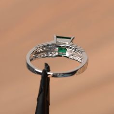 It is a lab emerald ring. The main stone is 6 mm*6 mm princess cut.weight about 0.93 carats. The basic metal is sterling silver and plated with rhodium. To change the metal to a solid gold (white/rose) or platinum is also available, please ask for a quotation if you want. You can also go to my shop Home for more elegant rings: https://www.etsy.com/shop/godjewelry?ref=hdr_shop_menu Emerald is the May birthstone More emerald rings: https://www.etsy.com/shop/godjewelry?section_id=20709240 Customiza Princess Cut Emerald Promise Ring, Cubic Zirconia Emerald Ring With Princess Cut, Princess Cut Cubic Zirconia Emerald Ring With Prong Setting, Emerald Princess Cut Ring With Prong Setting, Princess Cut Emerald Jewelry, Silver Emerald Ring With Princess Cut, Anniversary Princess Cut Cubic Zirconia Emerald Ring, Princess Cut Cubic Zirconia Emerald Ring For Anniversary, Silver Emerald Ring Princess Cut