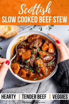 two hands holding a bowl of scottish slow cooked beef stew with bread in the background