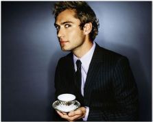 a man in a suit holding a cup and saucer