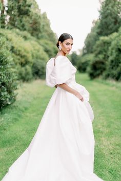 a woman in a white dress is standing on the grass