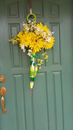 a green door with yellow flowers hanging from it's side and an umbrella attached to the front