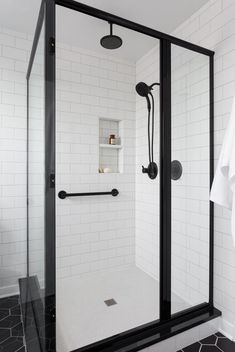 a walk in shower sitting next to a black and white tiled wall