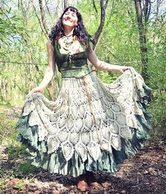 a woman standing in the woods wearing a dress