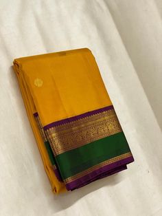 two yellow and green sarees laying on top of each other in front of a white sheet