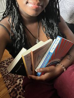 a woman is holding several books in her hands