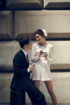 a man in a suit and tie standing next to a woman wearing a white dress