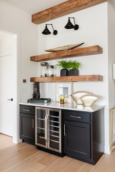 a kitchen with black cabinets and wooden shelves above the counter top, along with potted plants