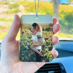 a person holding a small photo ornament in their hand while sitting in a car