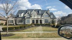 a large house is seen through the rear view mirror