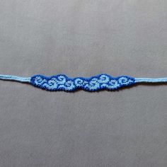 a blue and white beaded ribbon on a gray surface