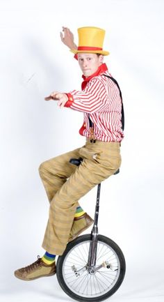 a young man riding on the back of a unicycle wearing a top hat