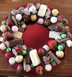 a cake decorated with strawberries, chocolates and marshmallows on a red plate