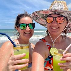 two women on the beach with drinks in their hands