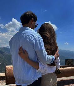 a man and woman embracing on top of a mountain