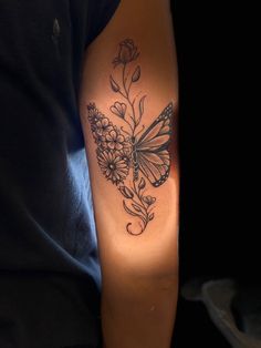 a butterfly tattoo on the arm with flowers and leaves around it's back side