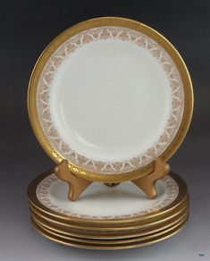 four gold and white plates stacked on top of each other